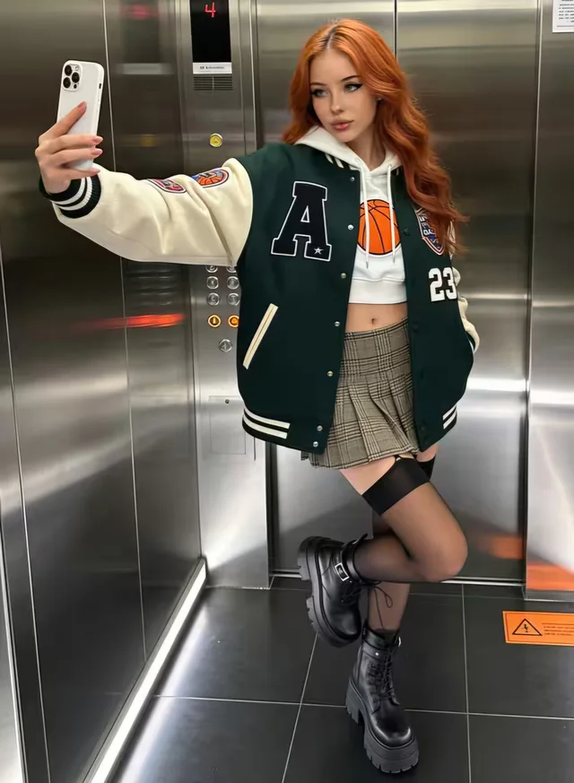 Adult AI-generated woman with red hair wearing a green varsity jacket